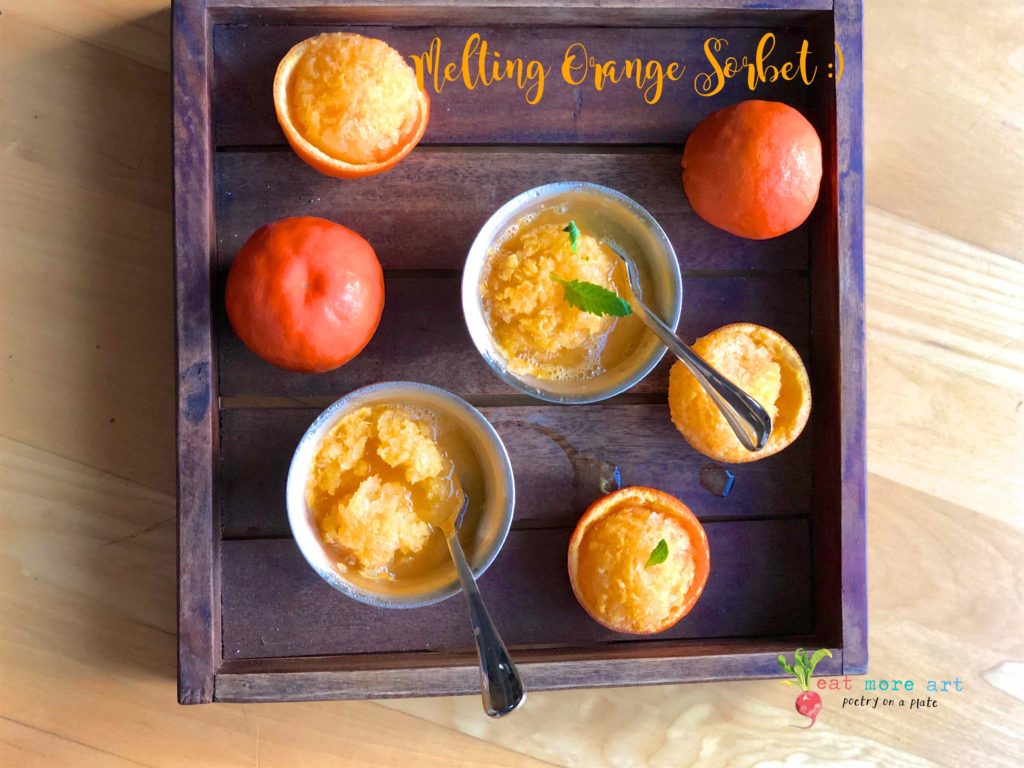 an overhead shot of melting orange sorbet bowls on a tray, with a couple of oranges.