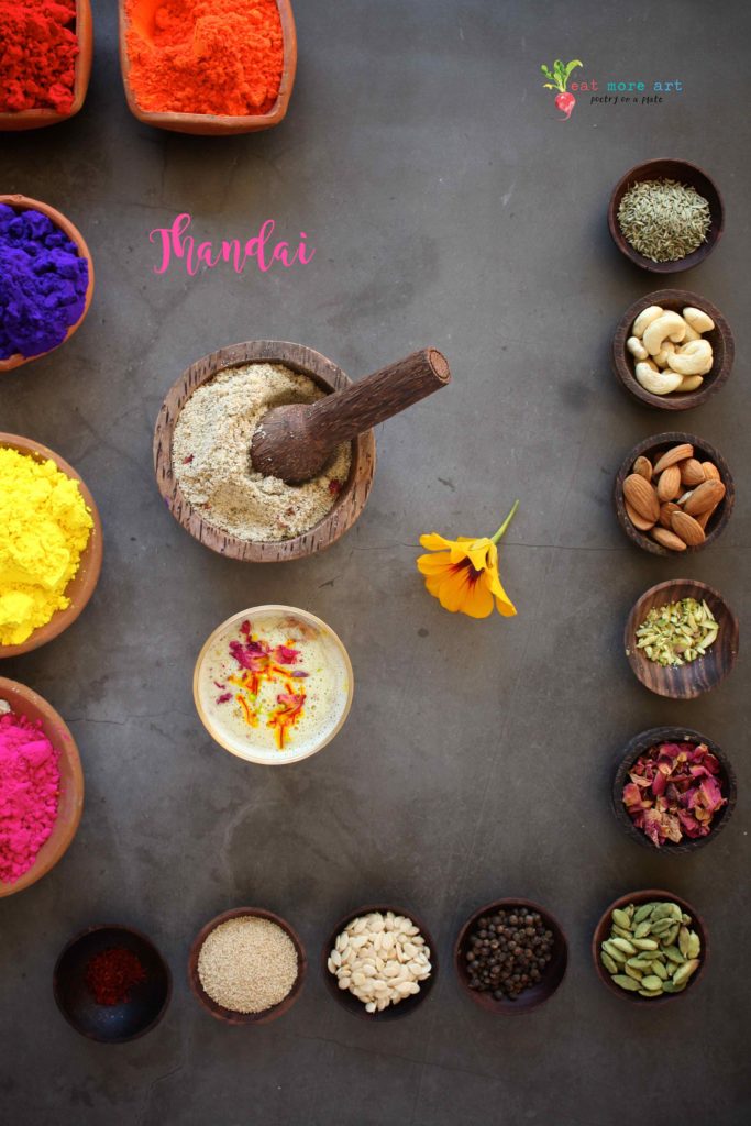 An overhead shot of a colorful tray of thandai, it's ingredients, and holi colors