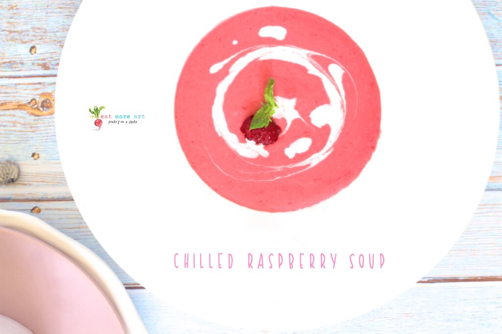 An overhead shot of chilled raspberry dessert soup garnished with mint and heavy cream