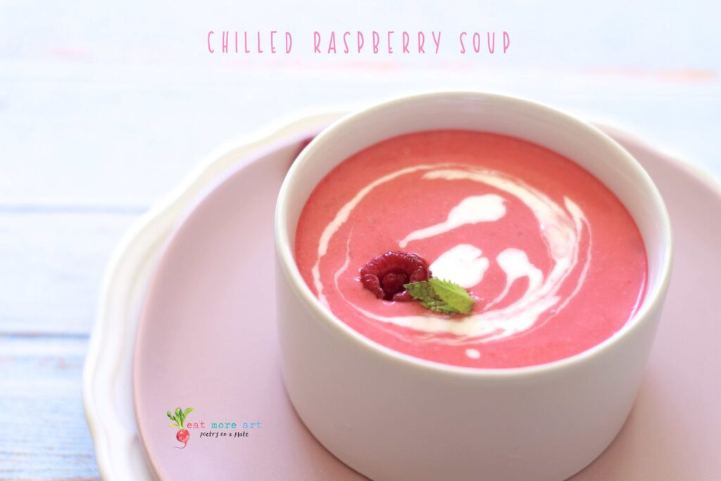 A side shot of chilled raspberry dessert soup garnished with mint and heavy cream