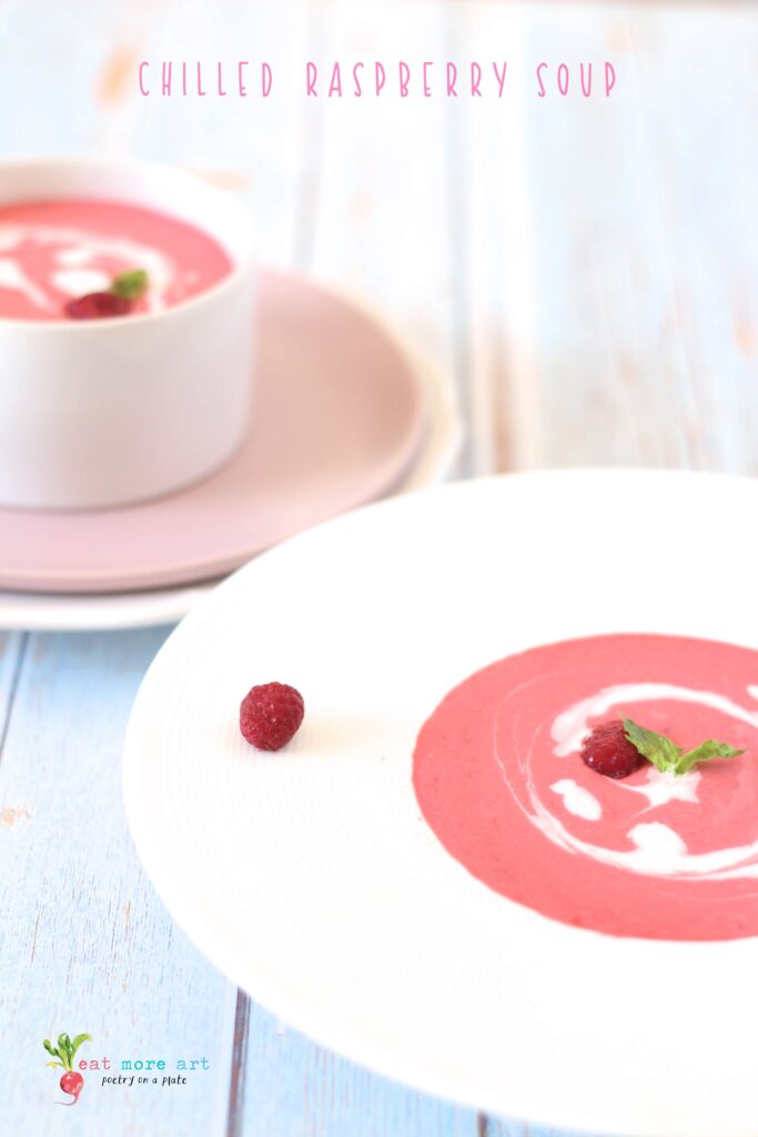 A side shot of chilled raspberry dessert soup garnished with mint and heavy cream