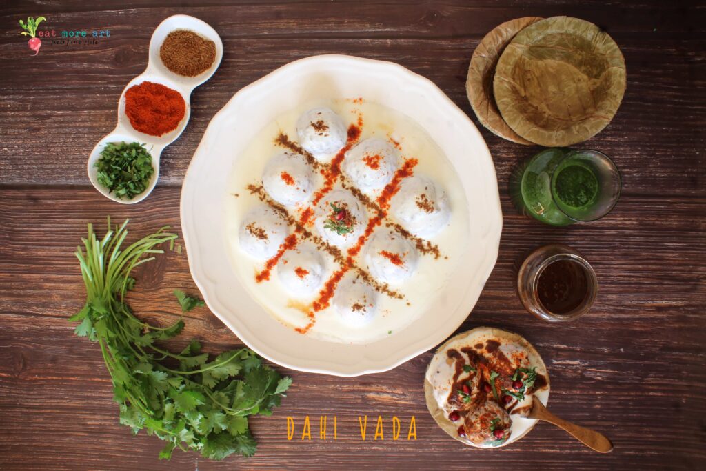 A horizontal overhead flat lay shot of dahi vada with condiments on the side