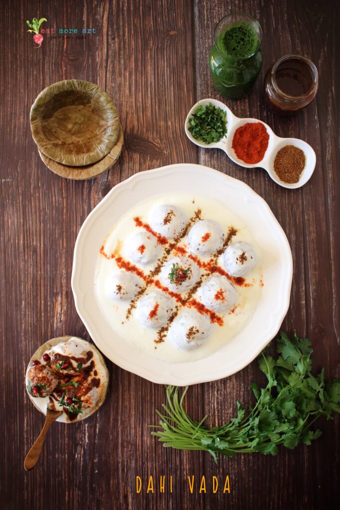 A vertical overhead flat lay shot of dahi vada with condiments on the side