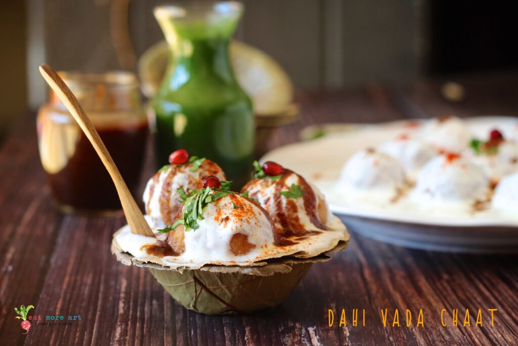 A closeup side shot of Dahi Vada with garnishes in a leaf bowl