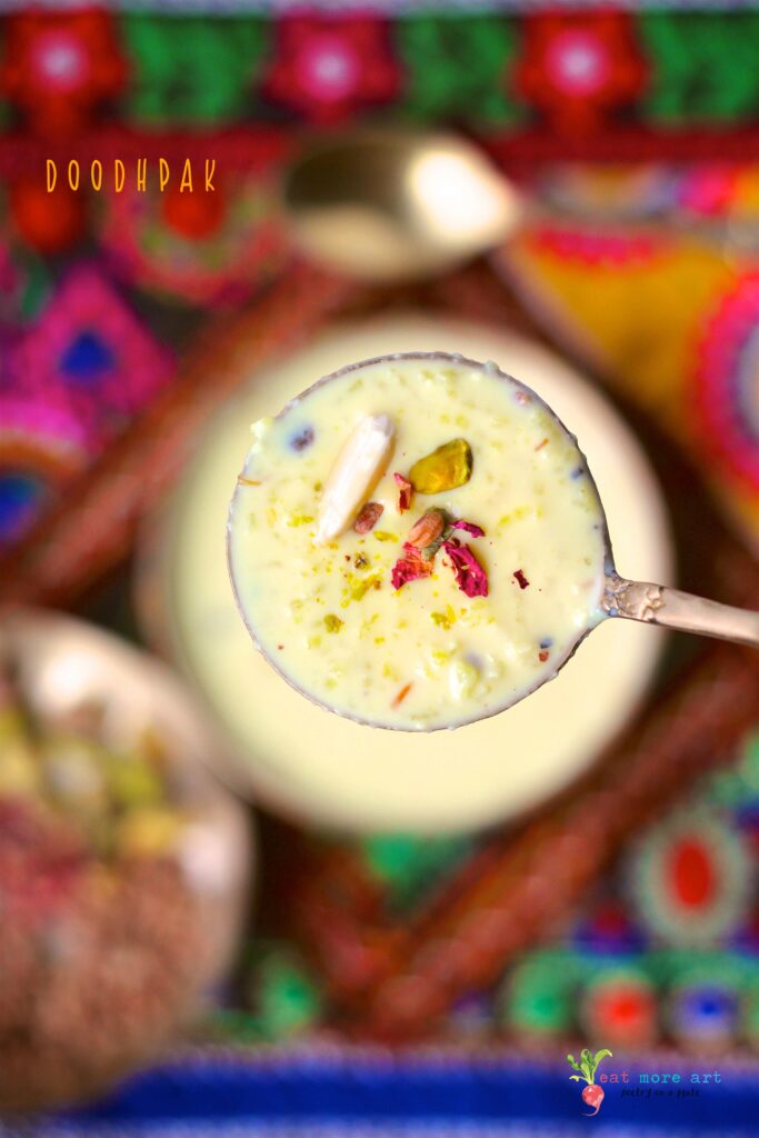 An closeup shot of a spoonfull of doodhpak over a colorful backdrop