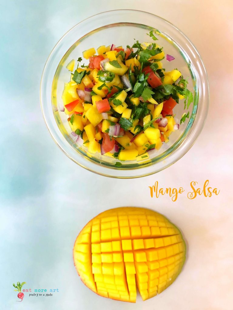 An overhead shot of a bowl of mango Salsa along with cut mango