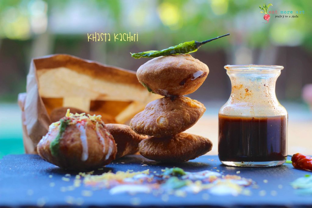 Khasta Kachori stacked up with green chili on top and chutney and khasta kachori chaat on the side