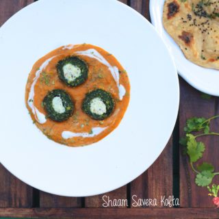 An overhead shot of plate of green spinach kofta with cut in half with white panner in center in orange color gravy served with a side of roti with teal color pool background