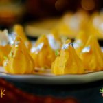 close up shot of yellow color modaks with edible silver foil, on a platter