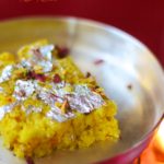 A side shot of saffron kalakand on a plate, garnished with dried rose petals and edible silver foil