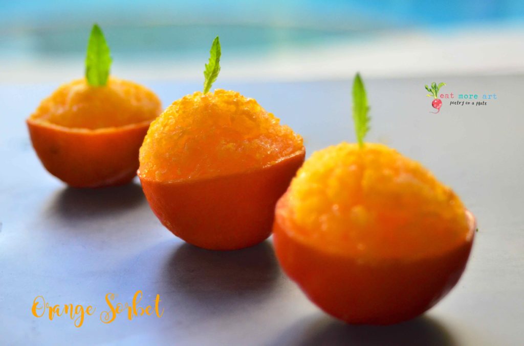a side shot of orange sorbet served in orange peel bowls, garnished with mint