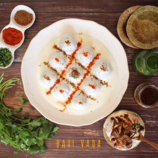 A horizontal overhead flat lay shot of dahi vada with condiments on the side